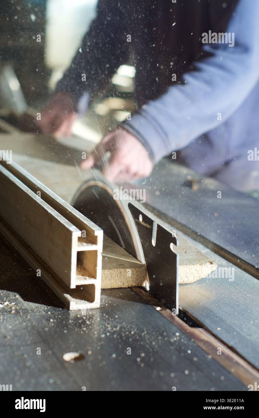 Ein Zimmermann schneidet mit einer freiliegenden Klinge einen Holzstreifen auf der Tischsäge Stockfoto