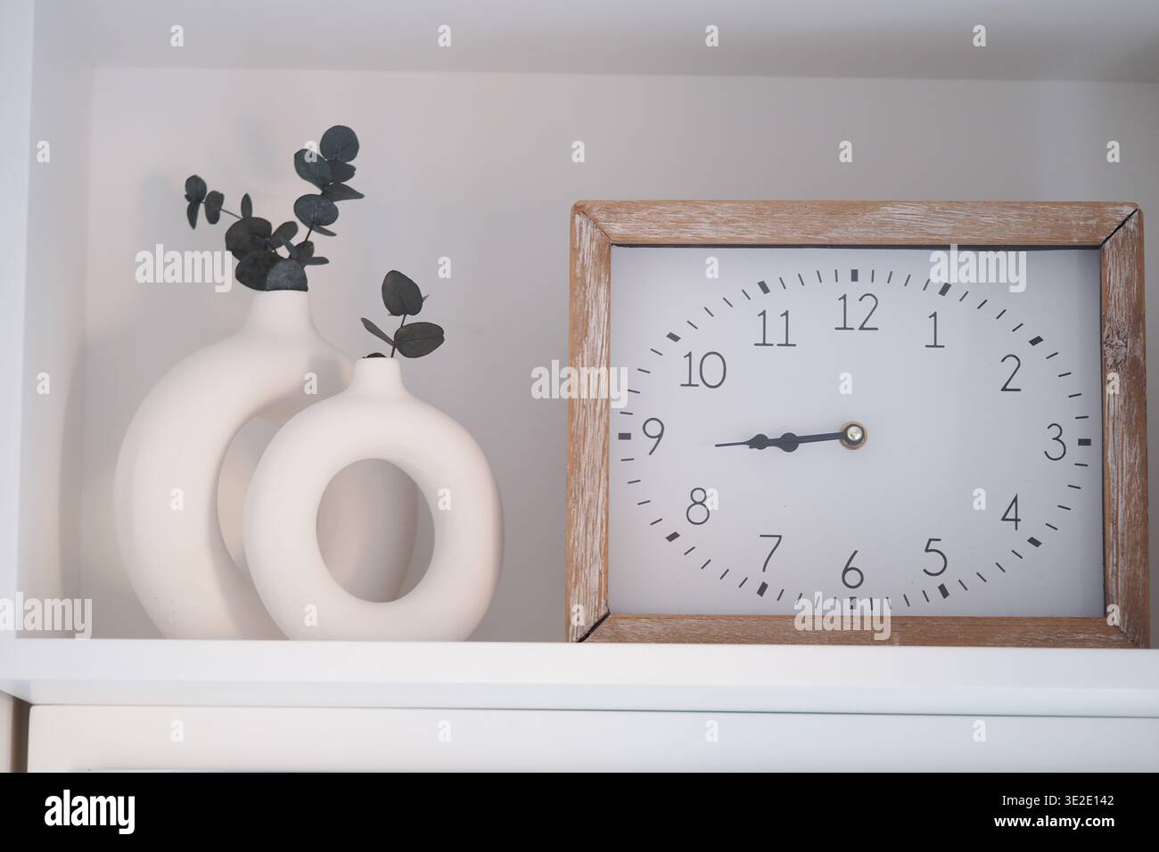 Dekoratives Regal mit Vasen und Uhr, die die Zeit anzeigt Stockfoto