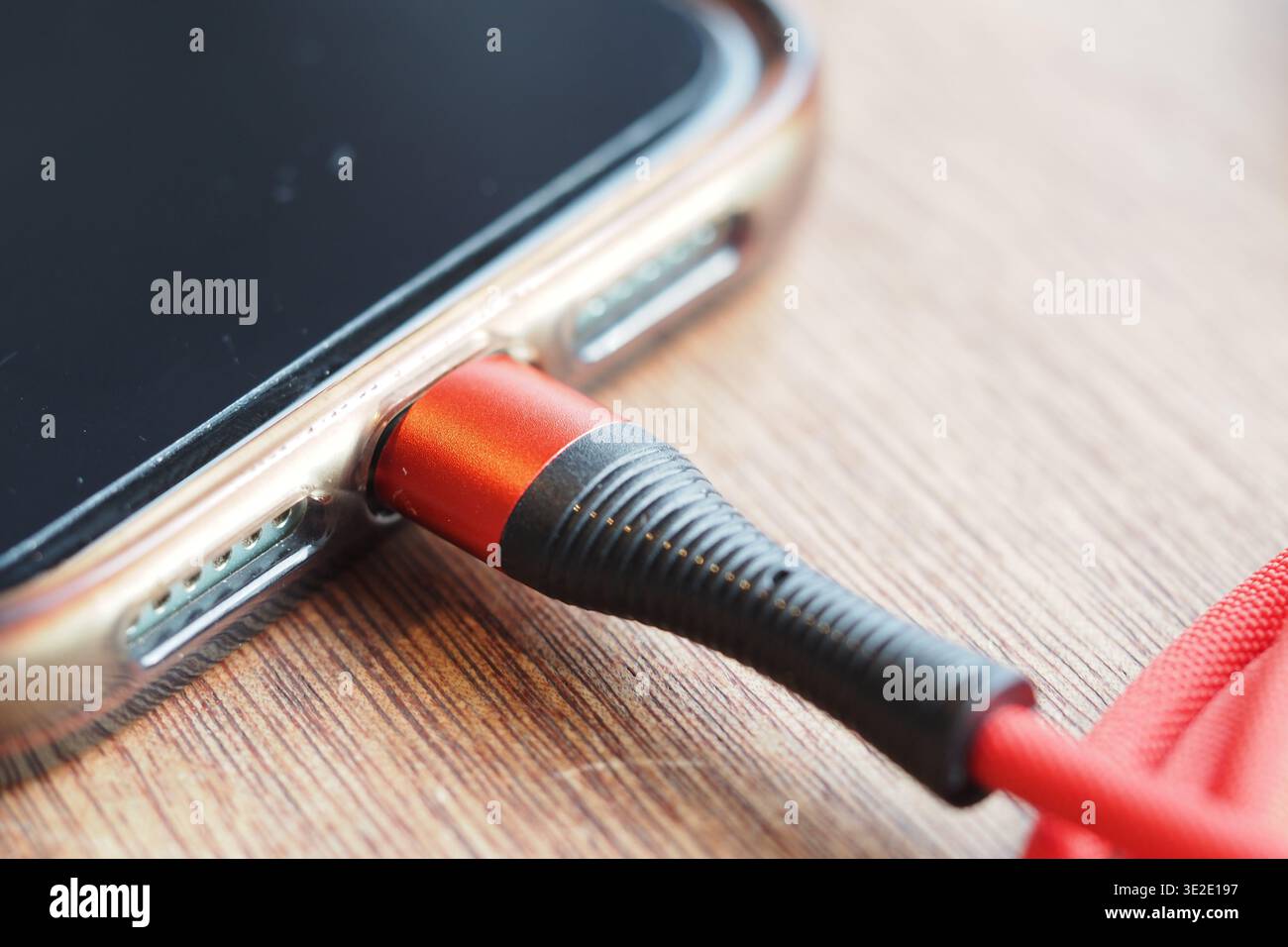 Telefon mit rotem Audiokabel auf Holztisch verbunden Stockfoto