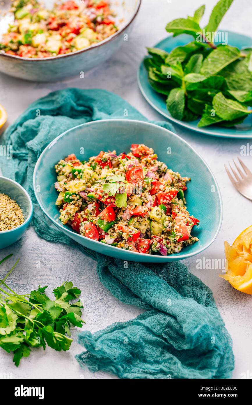 Farbenfroher Couscous-Salat mit Tomaten und Gurke in rustikaler Schüssel, garniert mit frischer Minze Stockfoto