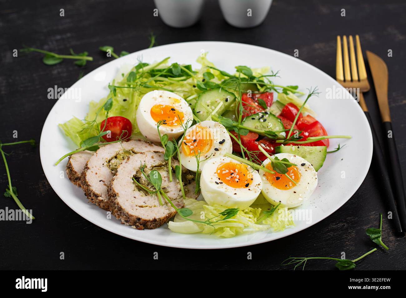 Gesunder Hühnersalat mit Eiern und frischem Gemüse auf dunklem Hintergrund Stockfoto
