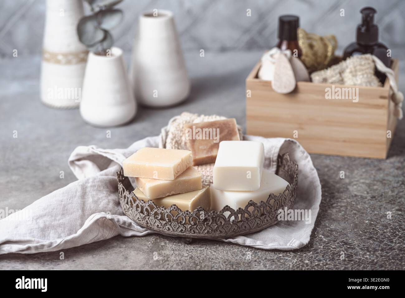 Verschiedene Seifen und Badezubehör auf einer Metallplatte auf grauem Hintergrund Stockfoto