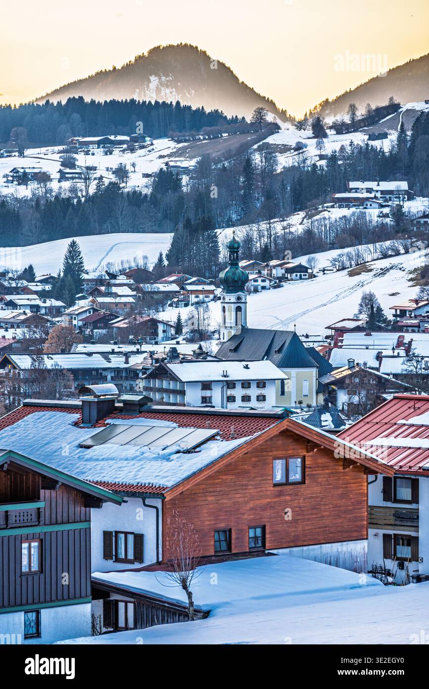REIT im Winkl Wintersportort, Blick auf die Stadt mit Kirche bei Sonnenuntergang. Deutsche alpen. Vertikal. Stockfoto