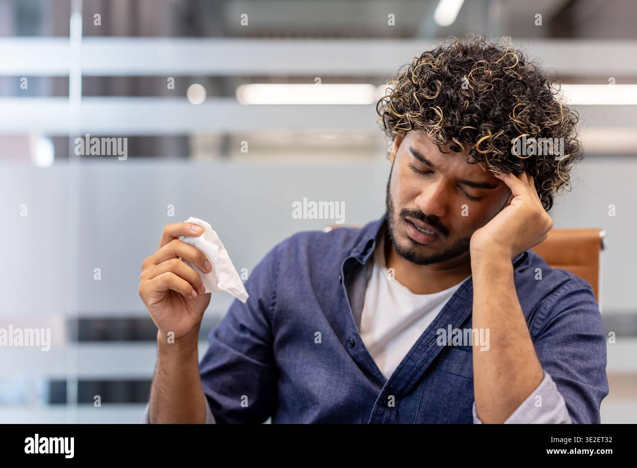 Nahaufnahme eines jungen Indianers in einem Büro, der eine Serviette hält und sich unwohl fühlt. Stockfoto
