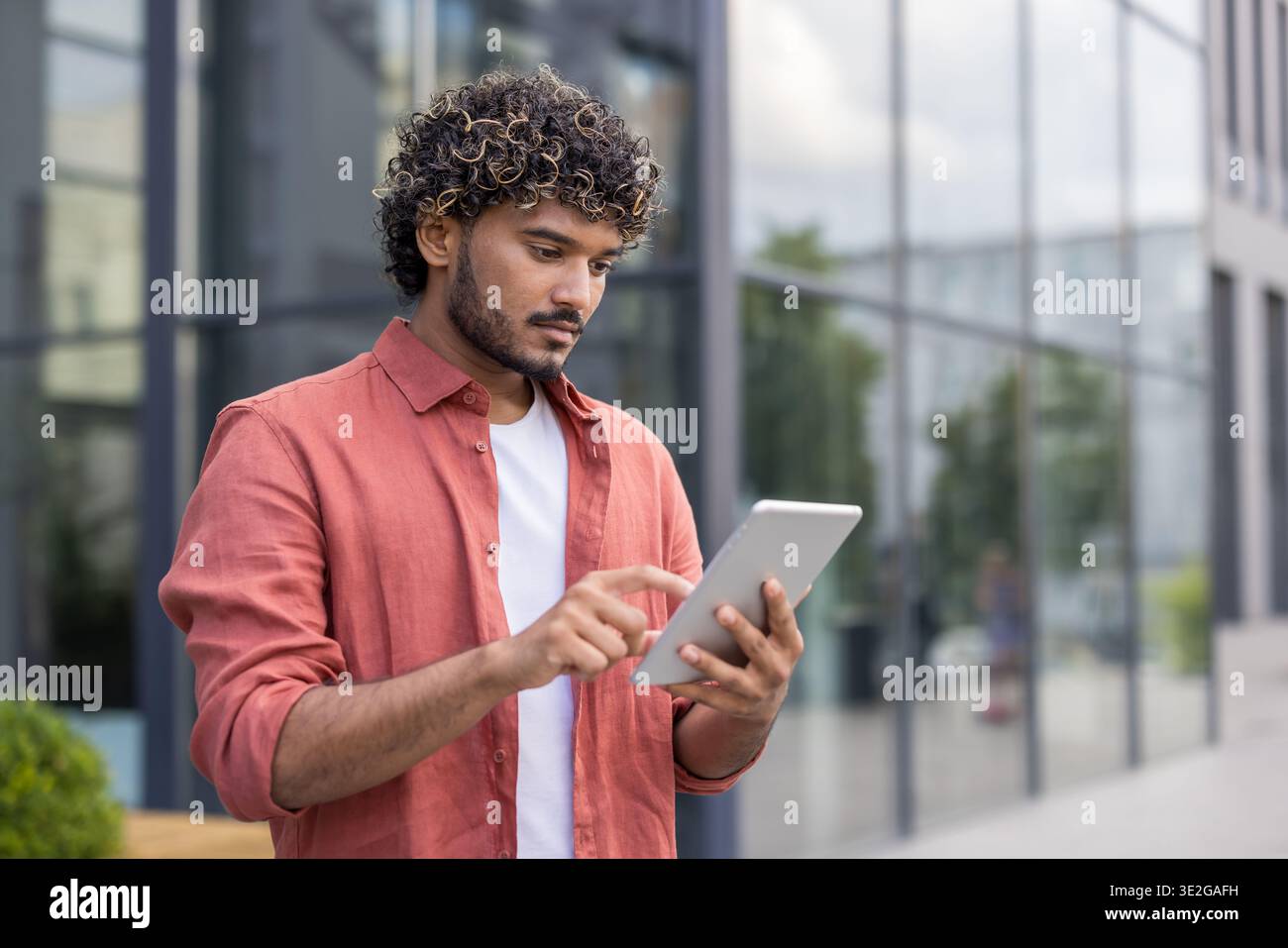 Nahaufnahme eines jungen Indianers, der draußen steht und eine Tablette benutzt. Stockfoto