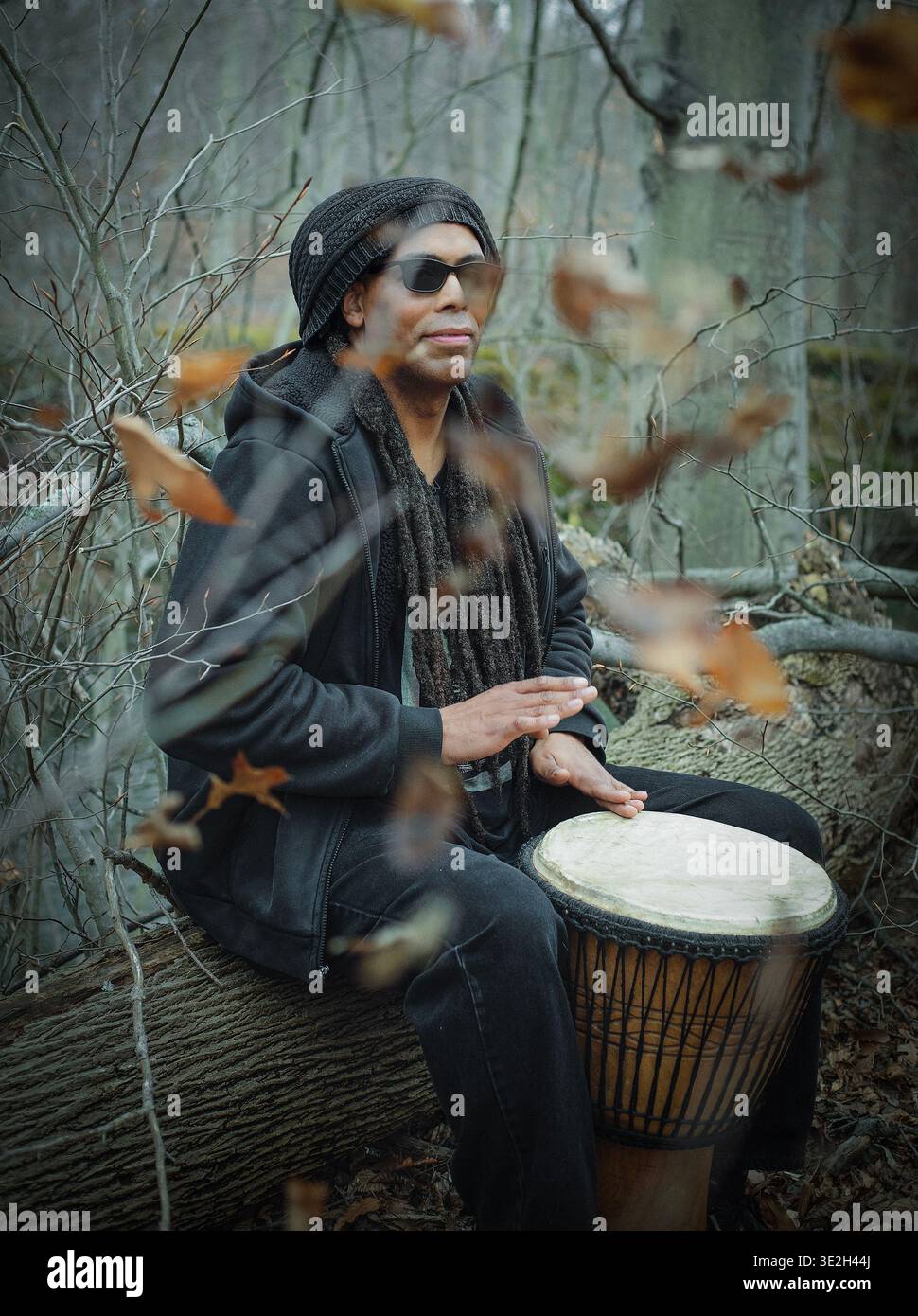 Männer spielen eine Djembe-Trommel durch einen Zweig Stockfoto
