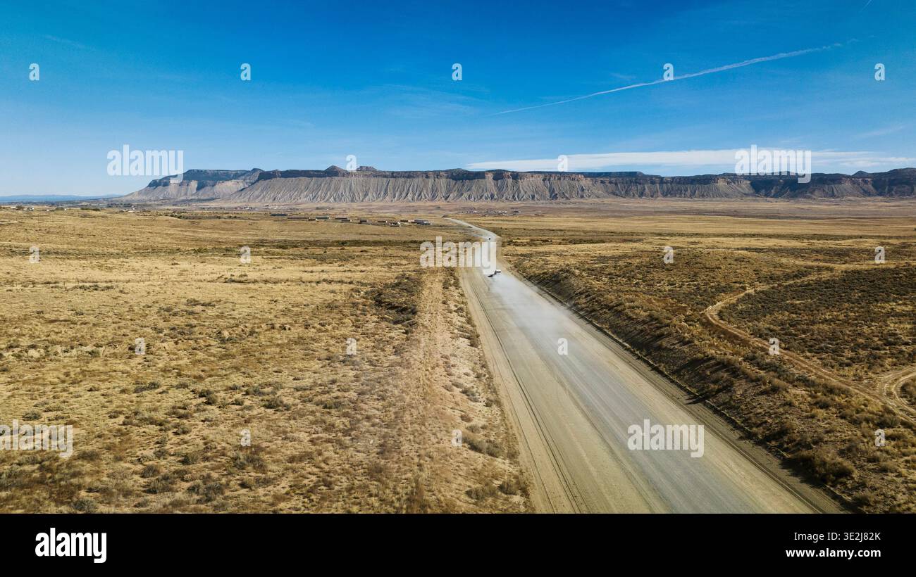 Luftaufnahme eines Lastwagens, der die staubige Wüstenstraße hinunterfährt. Stockfoto