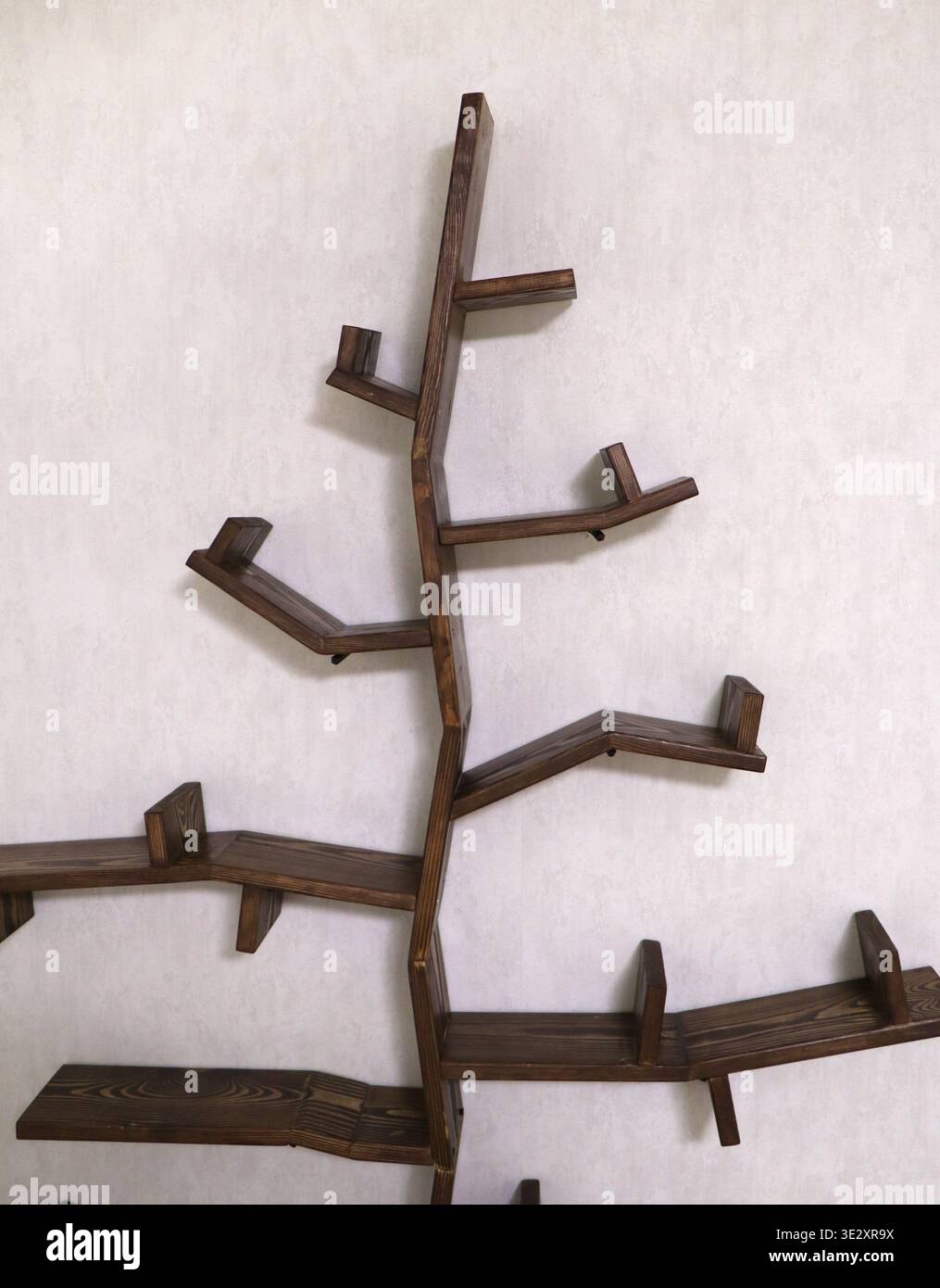 Modernes baumförmiges Holzregal an weißer Wand, Designer-Buch an der Wand Stockfoto
