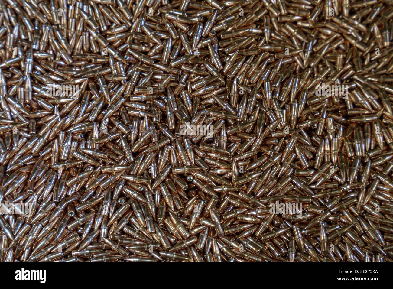 Großer Haufen von Gewehrkugeln und Kupfermunitionskomponenten in einer Fabrik oder einem Waffenbereich, Militärbedarf und Herstellungskonzept für Ballistik. Hoch q Stockfoto