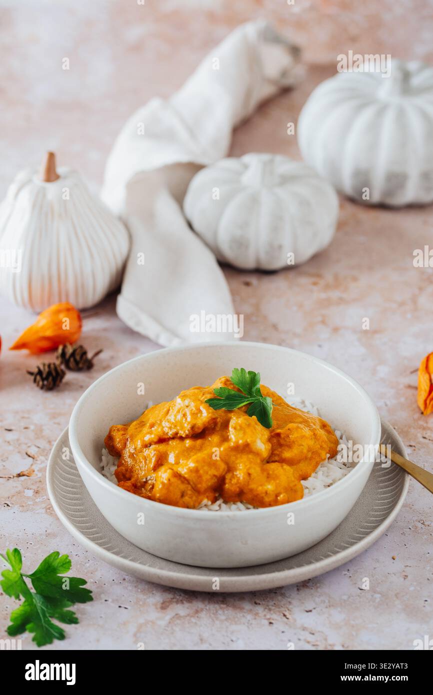 Indisches Tikka Masala Hühnercurry, Kürbiscurry, mit weißer Herbstdekoration, vertikal Stockfoto