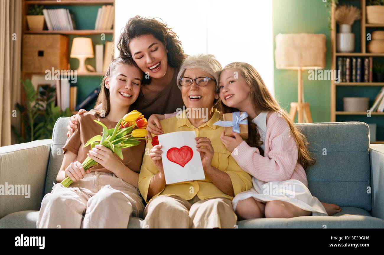 Herzliches, generationenübergreifendes Familienporträt mit Großmutter, Mutter und Enkelinnen, die zu Hause fröhlich gemeinsam feiern. Die fröhliche Szene Stockfoto