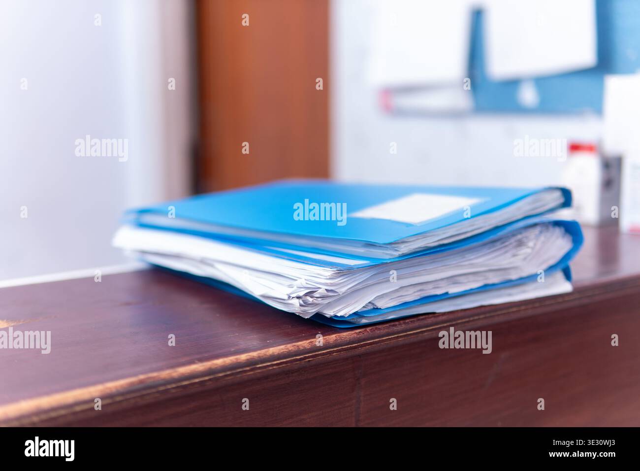 Nahaufnahme organisierter medizinischer Geschichtspapiere in einer blauen Mappe auf einem Rezeptionisten-Theken in einem Krankenhaus. Verwaltung und Gesundheitskonzept. Stockfoto