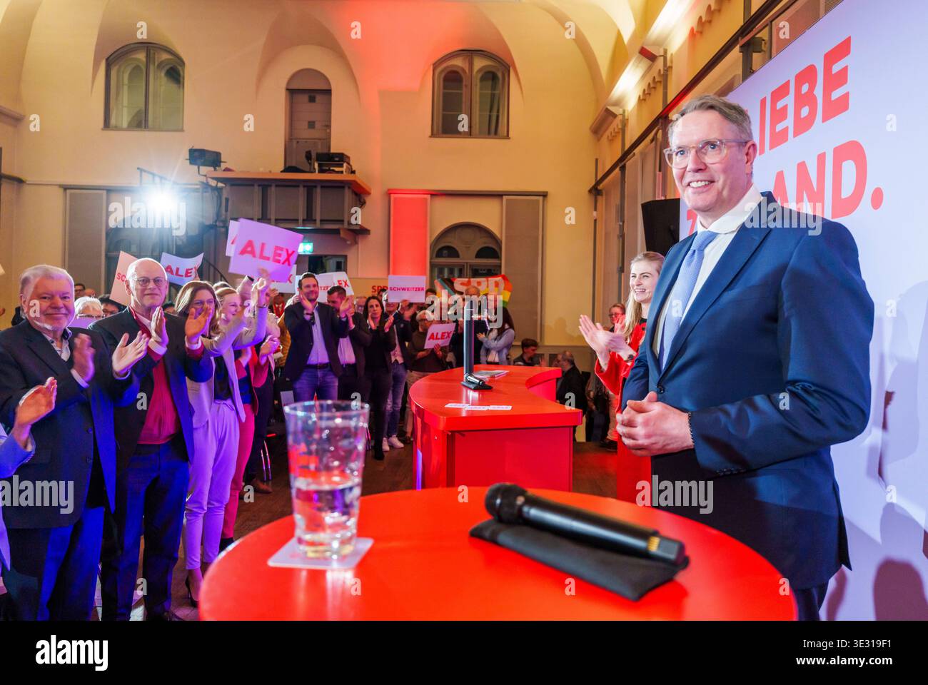 20. März 2026, Rheinland-Pfalz, Landau: Alexander Schweitzer (SPD), Spitzenkandidat für die bevorstehende Landtagswahl und Ministerpräsident von Rheinland-Pfalz, steht bei der Abschlussveranstaltung auf der Bühne. Kurt Beck (l-r, SPD), ehemaliger Ministerpräsident von Rheinland-Pfalz, Rudolf Scharping (SPD), ehemaliger Ministerpräsident von Rheinland-Pfalz, und Sabine Bätzing-Lichtenthäler (SPD), Fraktionsvorsitzende und Landesvorsitzende der SPD Rheinland-Pfalz, stehen zusammen im Publikum. SPD-Abschlussveranstaltung „Alexander Schweitzer Tour“ zur anstehenden Landtagswahl in Rheinland-Pfalz wi Stockfoto