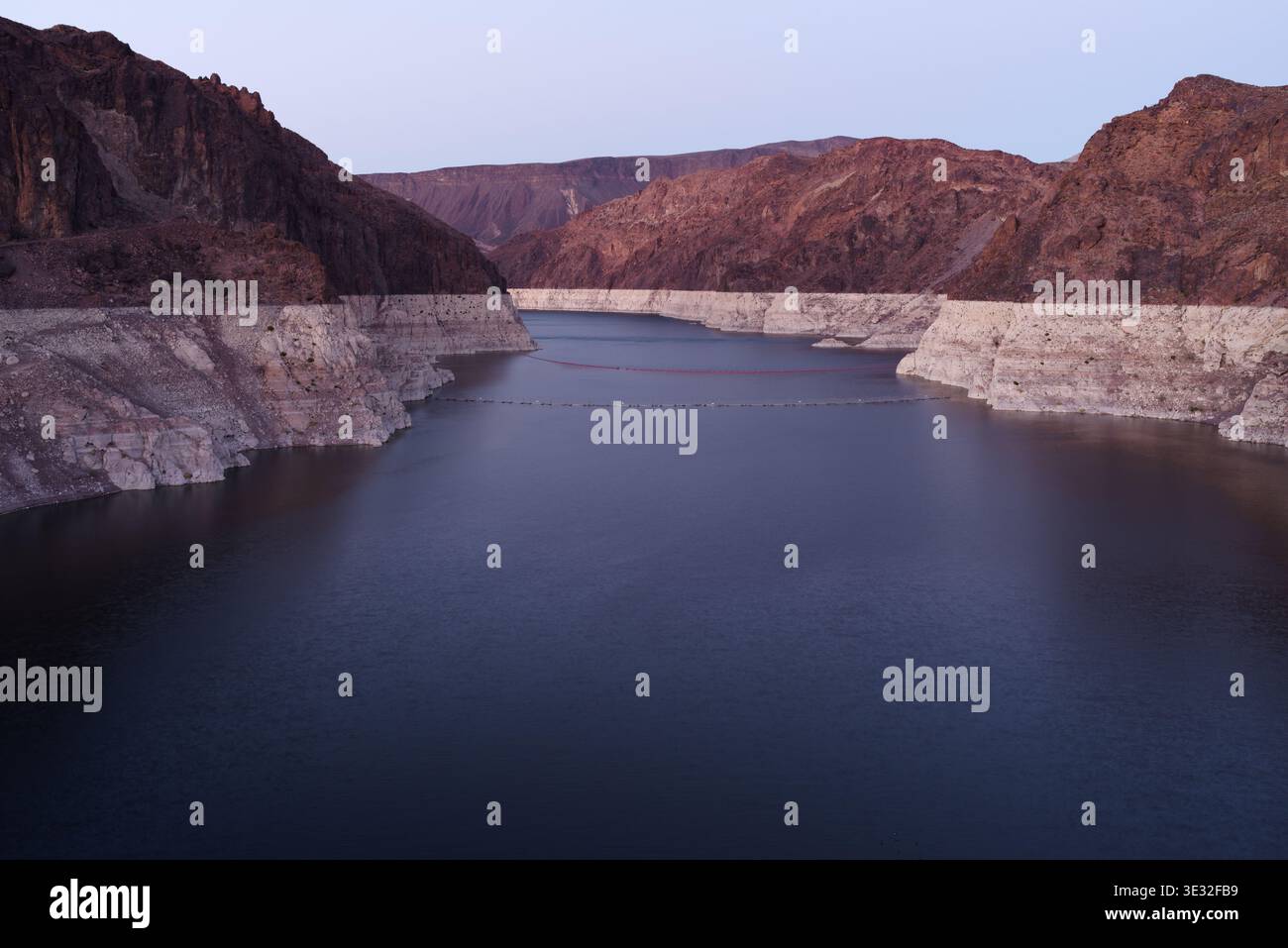 Panoramablick flussaufwärts auf den Hoover-Staudamm mit Blick auf Lake Mead, mit Stauwasser, umliegenden Bergen und sichtbaren Wasserstandmarkierungen. Stockfoto