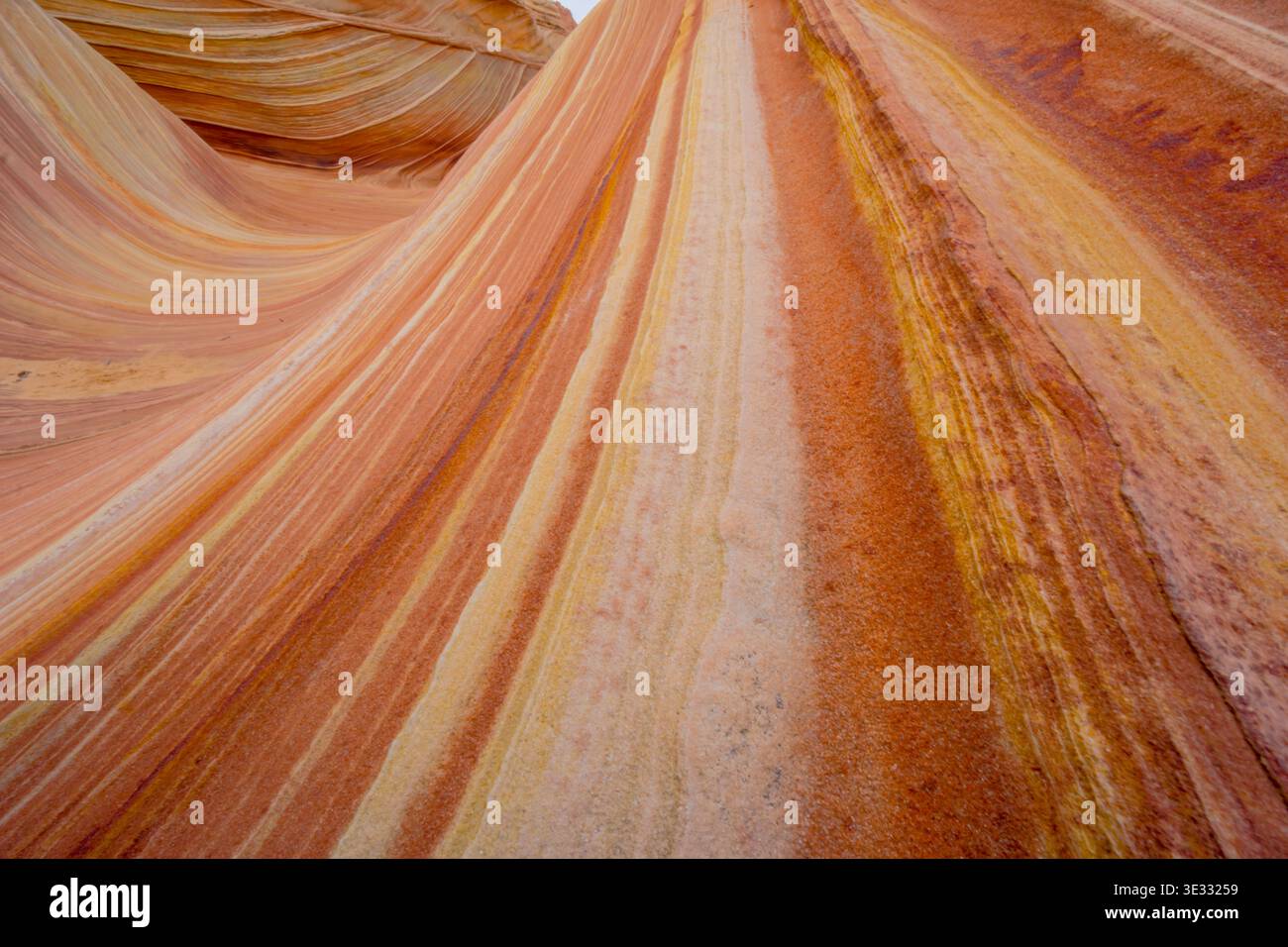 Das Bild zeigt eine felsige, orange und braune Landschaft mit viel Textur. Die Farben und Muster der Felsen erzeugen ein Gefühl von Tiefe und Bewegung, Stockfoto