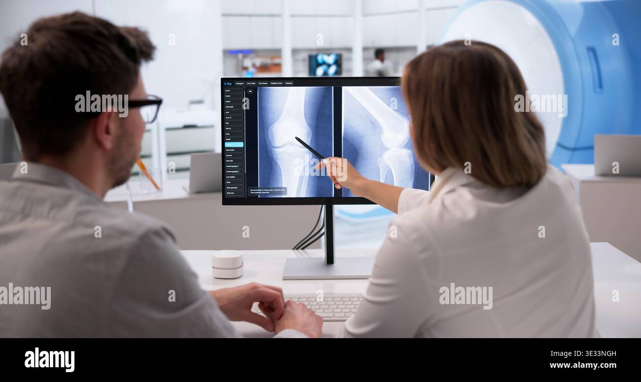 Medizinisches Fachpersonal, das vor der Operation die Knieröntgenuntersuchung auf dem Computerbildschirm analysiert Stockfoto