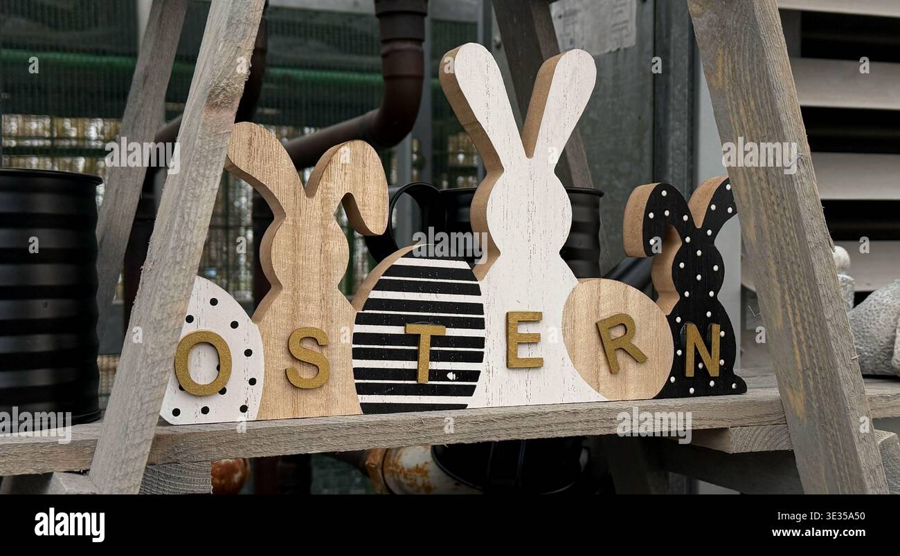 Dekorative Holzhasen und Eier mit der Schreibweise „OSTERN“ auf einem Regal Stockfoto