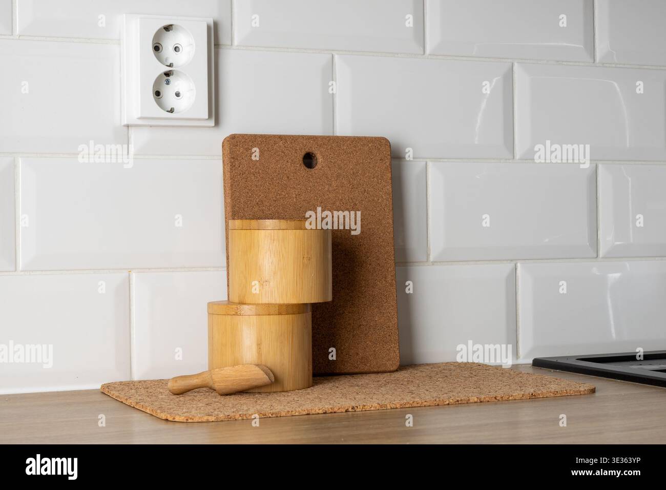 Dieses Bild zeigt eine saubere und moderne Kücheneinrichtung mit Fokus auf nachhaltige Materialien. Auf einer hellen hölzernen Arbeitsplatte, zwei zylindrisch Stockfoto