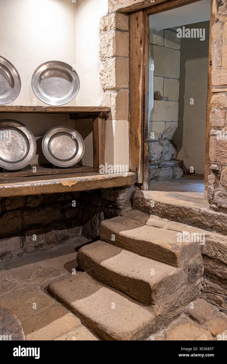 Der abgenutzte Stein tritt in die alte Küche in Haddon Hall, Bakewell, Derbyshire, England, Großbritannien Stockfoto