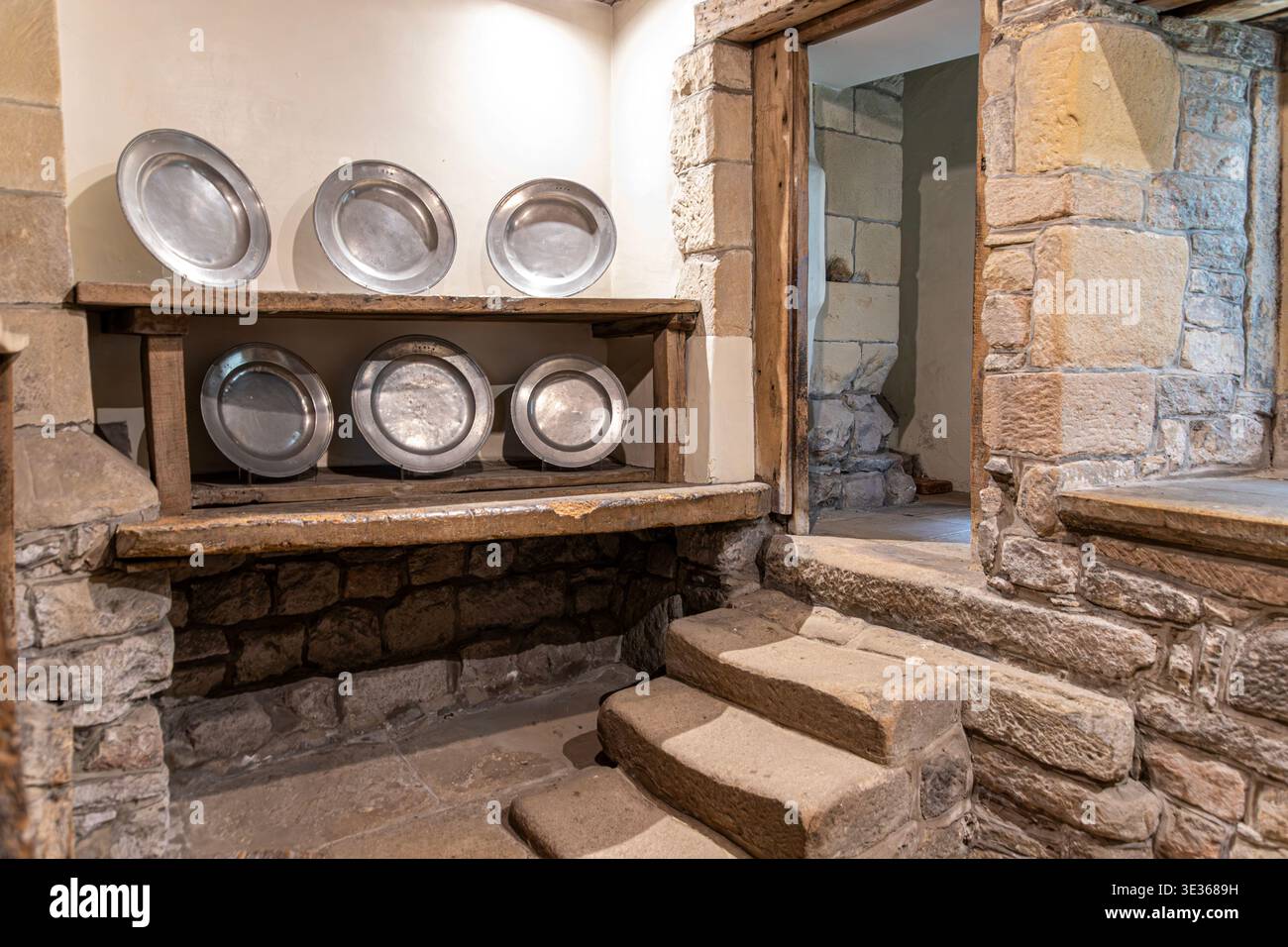 Der abgenutzte Stein tritt in die alte Küche in Haddon Hall, Bakewell, Derbyshire, England, Großbritannien Stockfoto