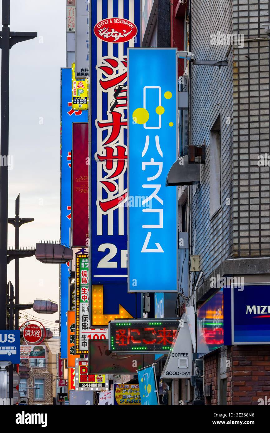 Vertikale beleuchtete Werbeschilder mit japanischem Text auf einem städtischen Stadtgebäude Stockfoto