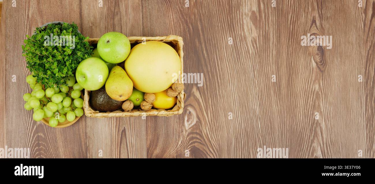 Korb mit frischem Obst und Gemüse auf einer hölzernen Oberfläche mit glattem Hintergrund. Züchten Sie frisches Obst und Gemüse in Korb. Stockfoto