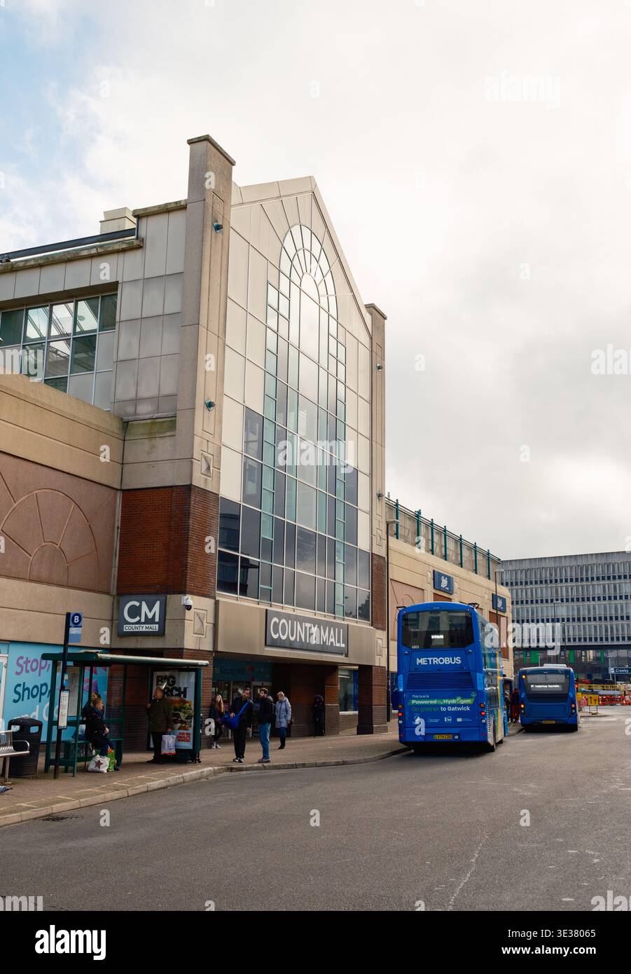 Bushaltestelle der County Mall in Crawley England mit Bussen und dem Einkaufszentrum mit Glasfassade in Schuss. Stockfoto