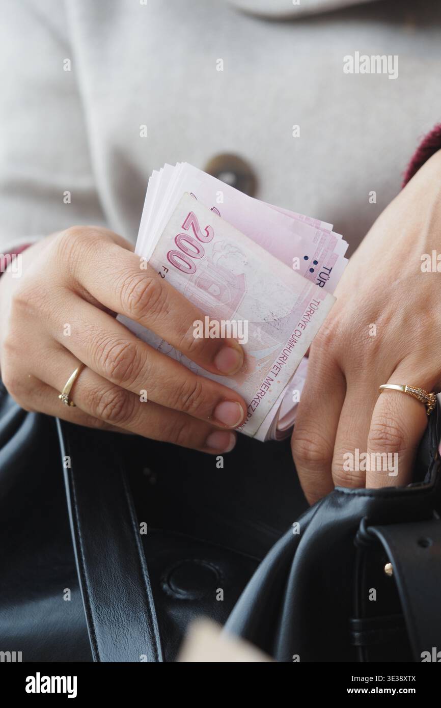 Ich zähle türkisches Lira-Geld, während ich eine Tasche an einem öffentlichen Ort halte Stockfoto