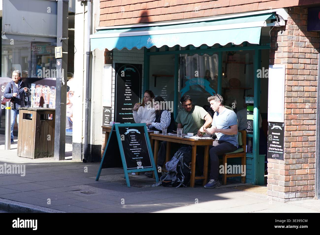 Gruppe von Freunden, die in einem Café mit grüner Markise auf der Hauptstraße in Lyndhurst, New Forest, Hampshire essen. Lyndhurst, England Stockfoto