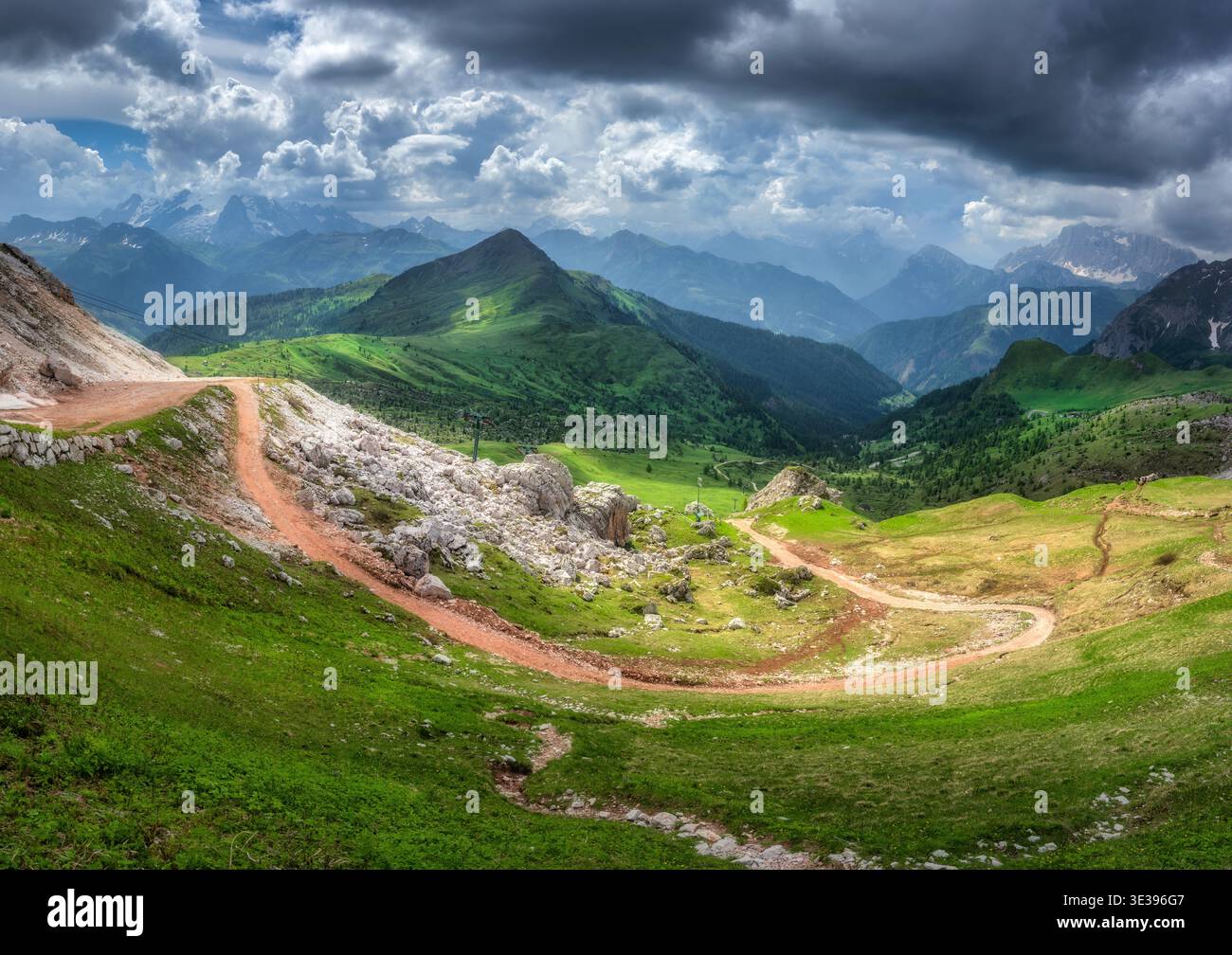 Gewundene Bergstraße in einem lebhaften grünen Tal, alpine Berge Stockfoto