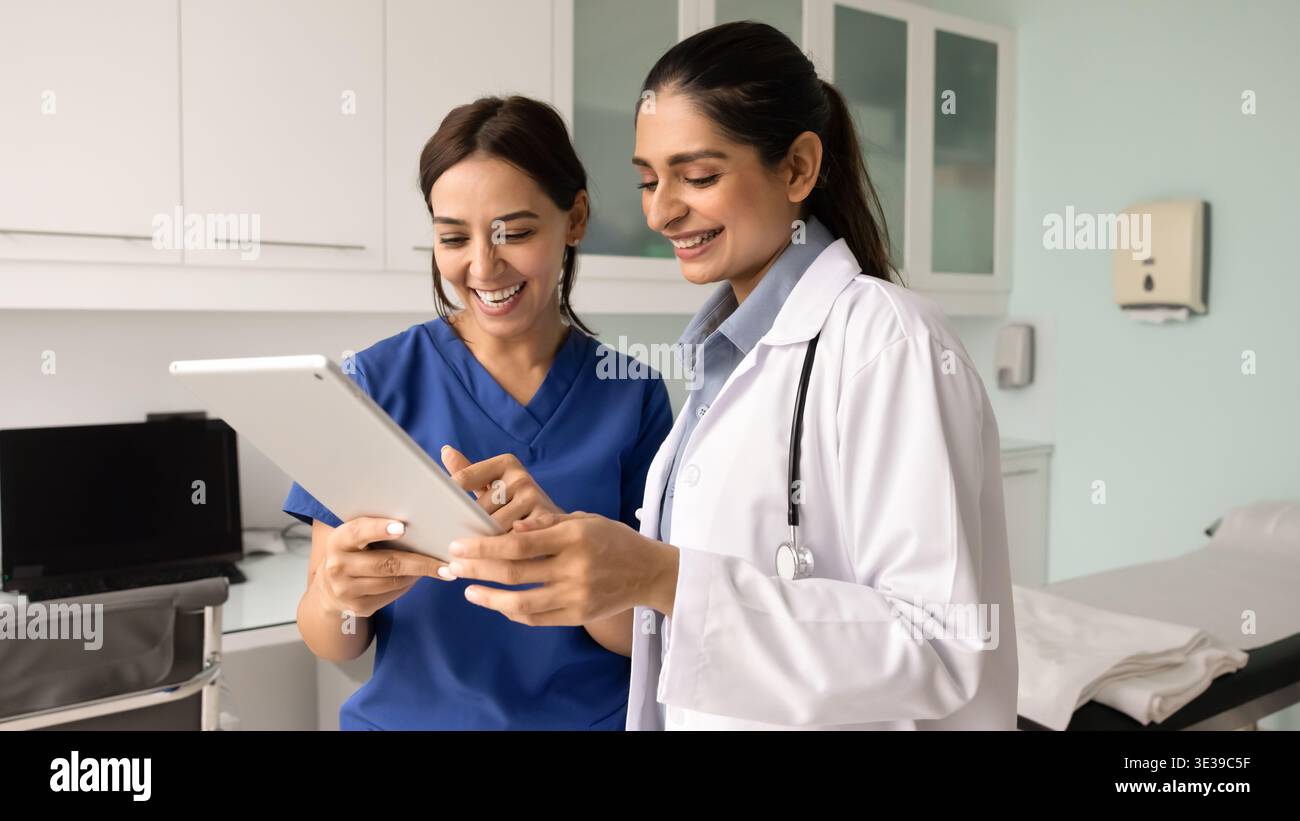 Zwei Ärztinnen überprüfen positive Aktualisierungen der Patientenerholung auf einem Tablet Stockfoto
