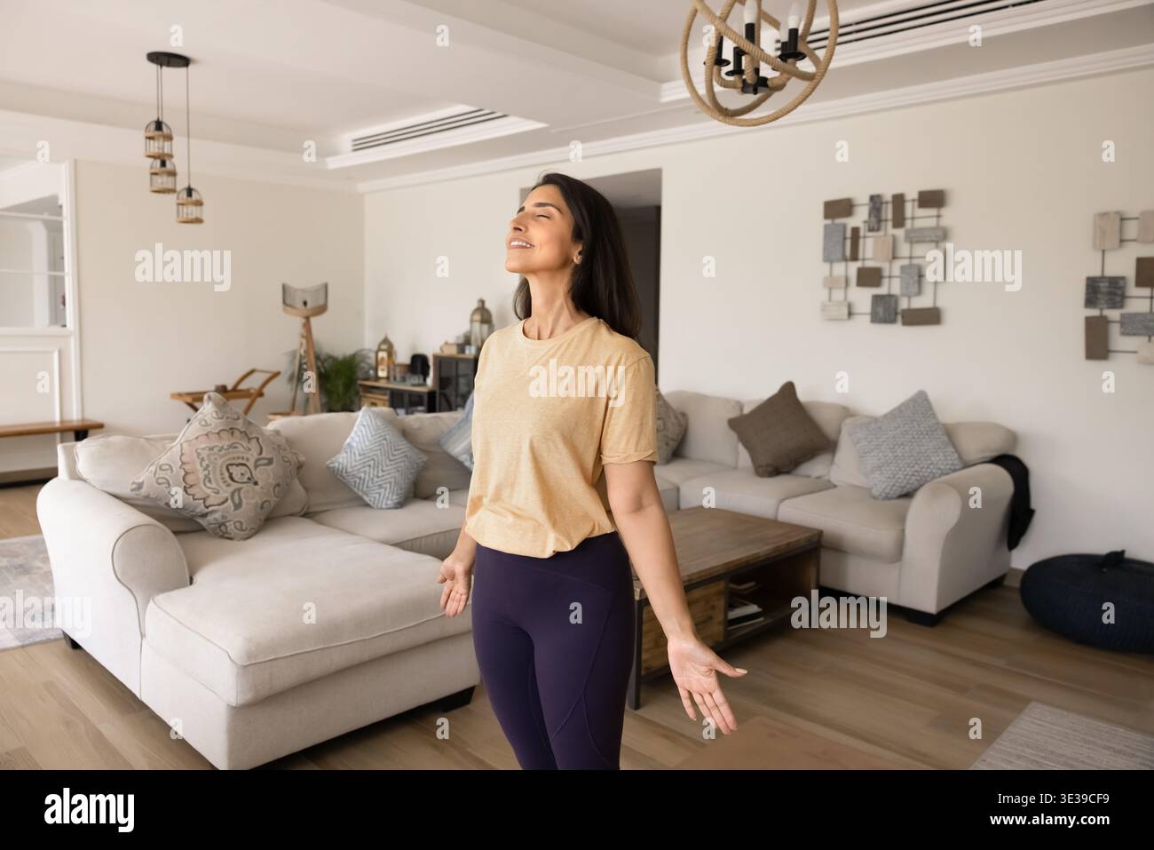 Junge Yogini-Frau, die ruhig im gemütlichen Wohnzimmer steht Stockfoto