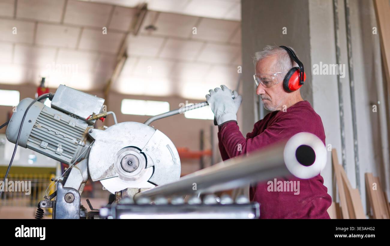Leitender Handwerker, der Holz mit Schutz in der Werkstatt schneidet Stockfoto