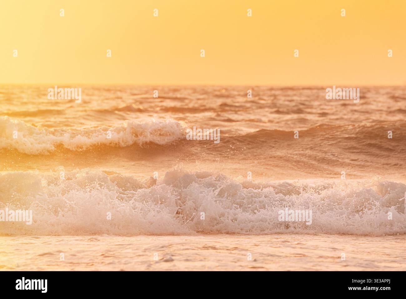 Sonnenuntergang über dem Meer. Riplpe Meerwasseroberfläche mit kleinen Wellen. Wasserschaumspritzer. Wunderschöne Naturlandschaft Stockfoto
