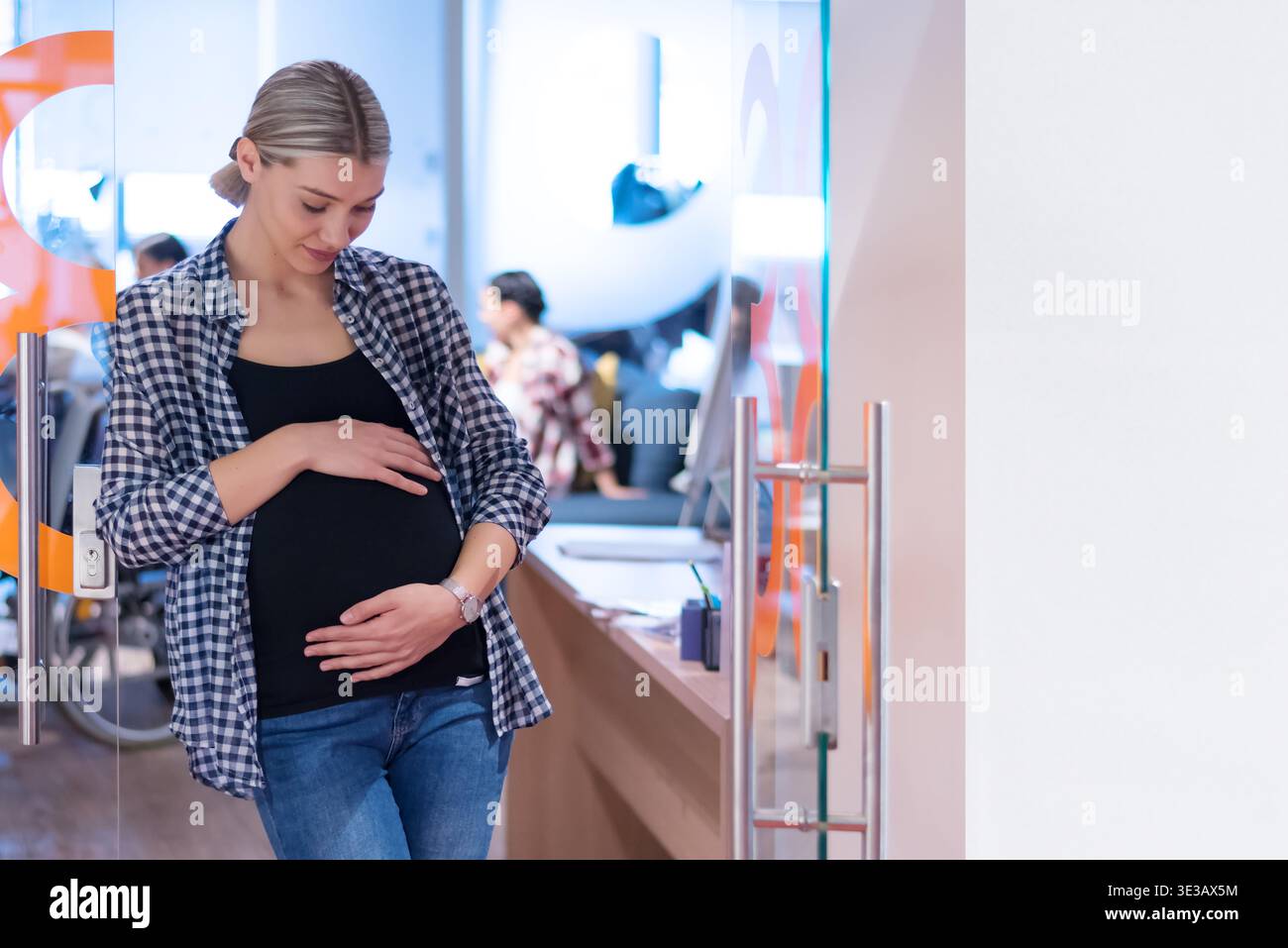 Junge schwangere Frau in ein modernes Büroumfeld. Konzept der Work-Life-Balance, weibliche Empowerment, Karriere in der Schwangerschaft und modernes Busin Stockfoto
