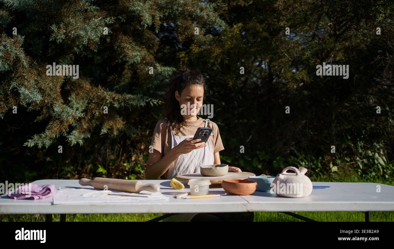 Eine Künstlerin, die ihre Keramikarbeiten auf einem Tisch in einem Outdoor-Studio fotografiert Stockfoto