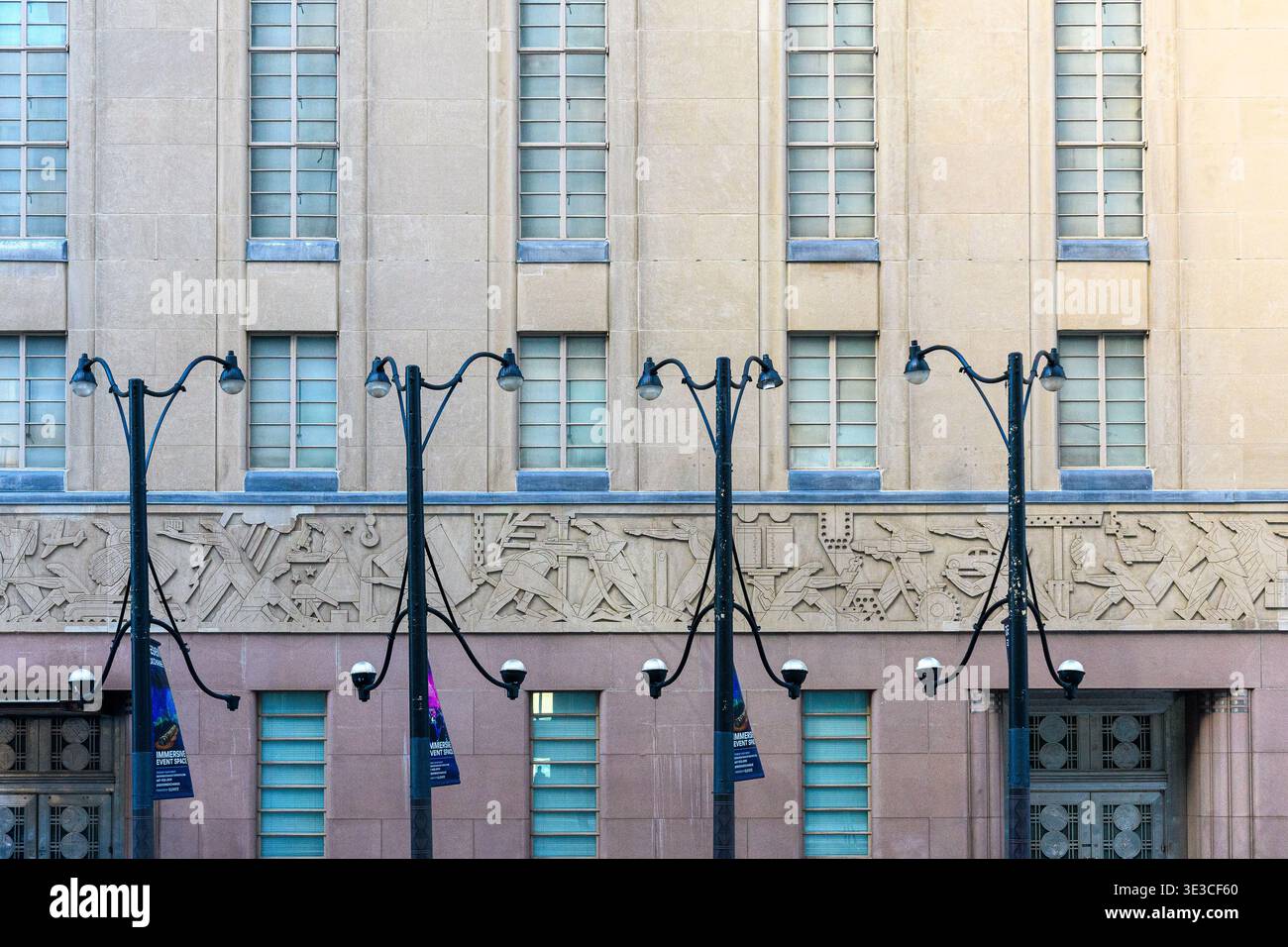 Toronto Stock Exchange Gebäude. Eine Reihe von Straßenlaternen steht vor einer Gebäudefassade mit hohen Fenstern und dekorativen Reliefplatten. Stockfoto
