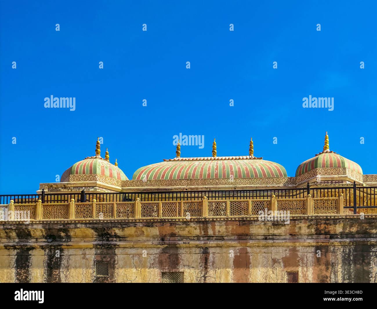 Jaipur, Indien, 19.02.2020. Ein Niedrigwinkelfoto mit den bunten gestreiften Kuppeln und den komplizierten Steingeländern des historischen Amer Fort unter einem Vigleie Stockfoto