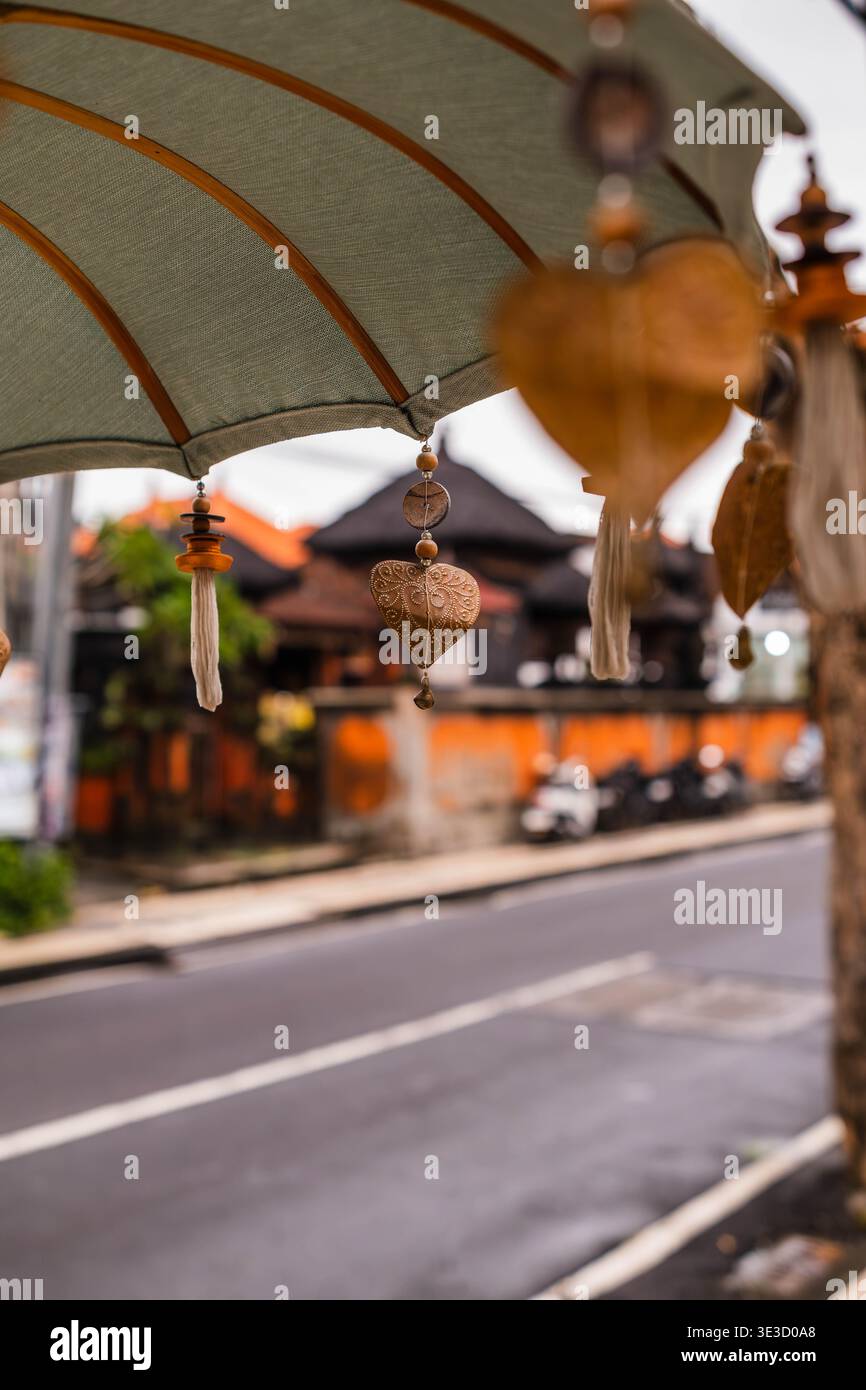 Prunkvoller balinesischer zeremonieller Regenschirm mit Blick auf eine nasse Stadtstraße Stockfoto
