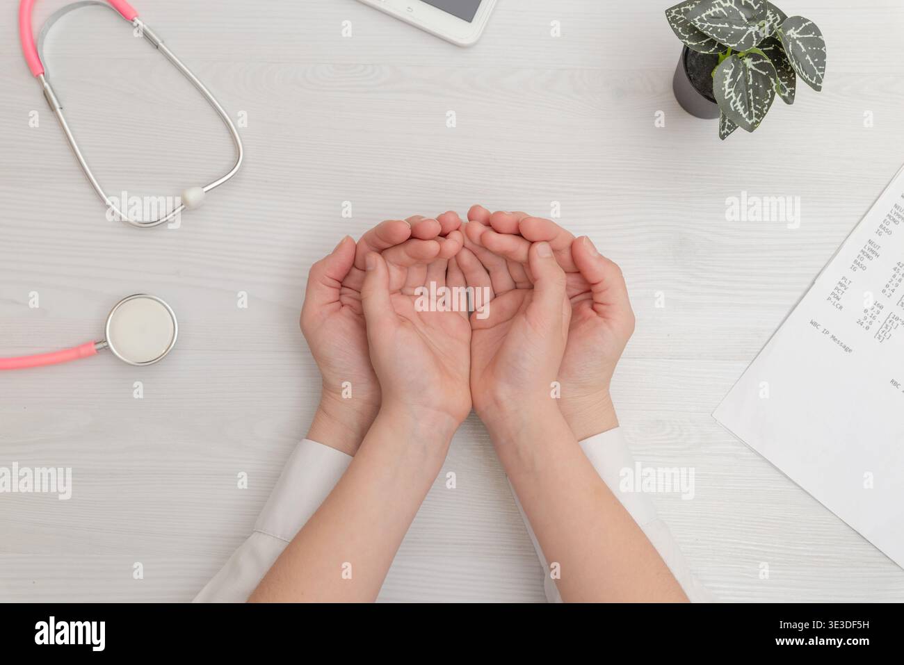 Arzt, der die Hände des Patienten in liebevoller Geste auf dem medizinischen Schreibtisch hält, steht für Vertrauen, Unterstützung und Gesundheitsschutzkonzept Stockfoto