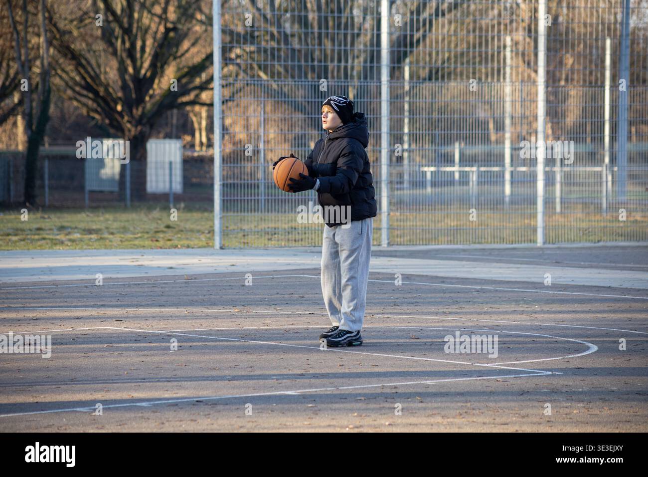 Teenager, der Basketball auf dem Platz im Freien hält, bereit für das Lifestyle-Konzept des Spielsports Stockfoto