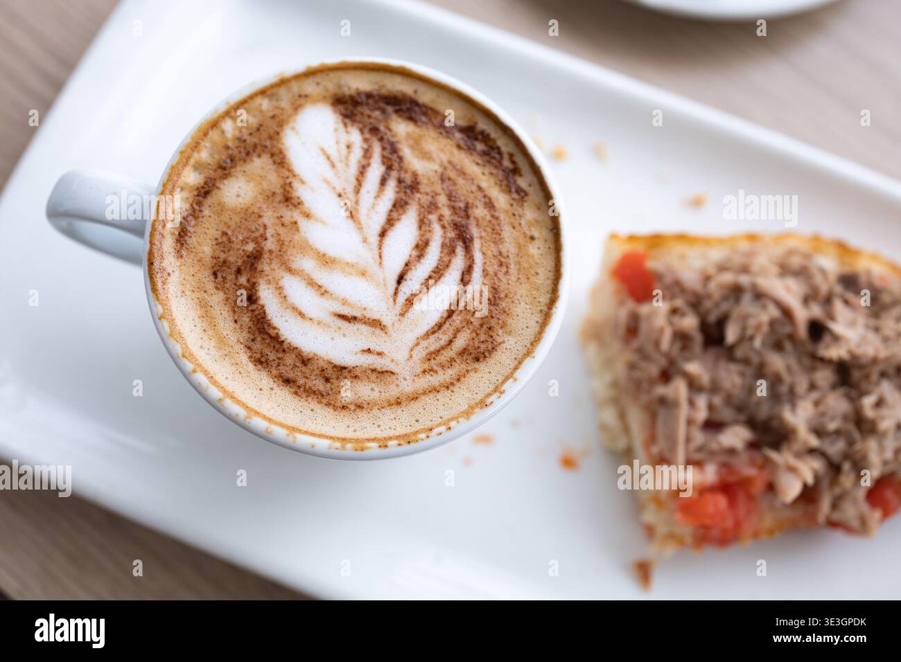 Köstliches Frühstück mit einem Cappuccino mit Latte Art und einem Toast mit Tomaten und Thunfisch Stockfoto