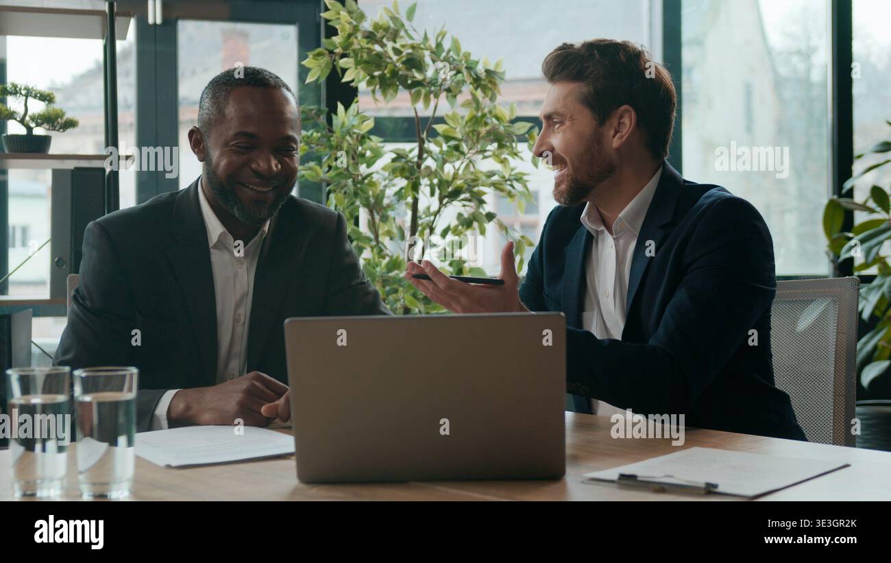 Verschiedene Männer Kollegen Geschäftsteams tauschen Ideen aus Laptop-Arbeit diskutieren im Büro Meeting lächelnd zwei multirassische Geschäftsleute freuten sich glücklich Stockfoto