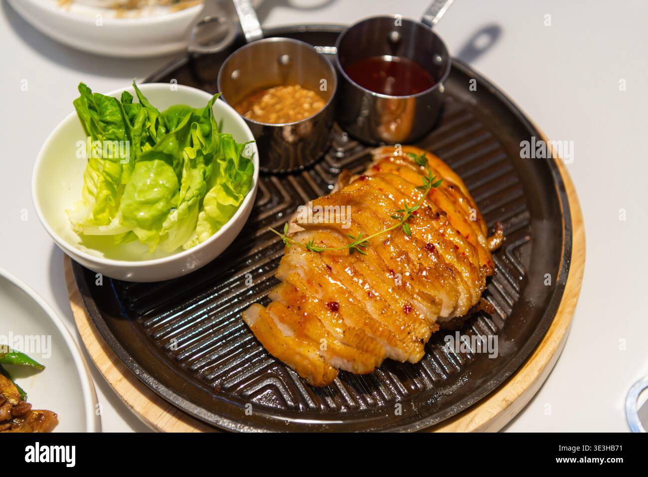 Peking, China - 19. März 2026: Schweinehals auf einer gusseisernen Platte mit Dips gegrillt. Stockfoto