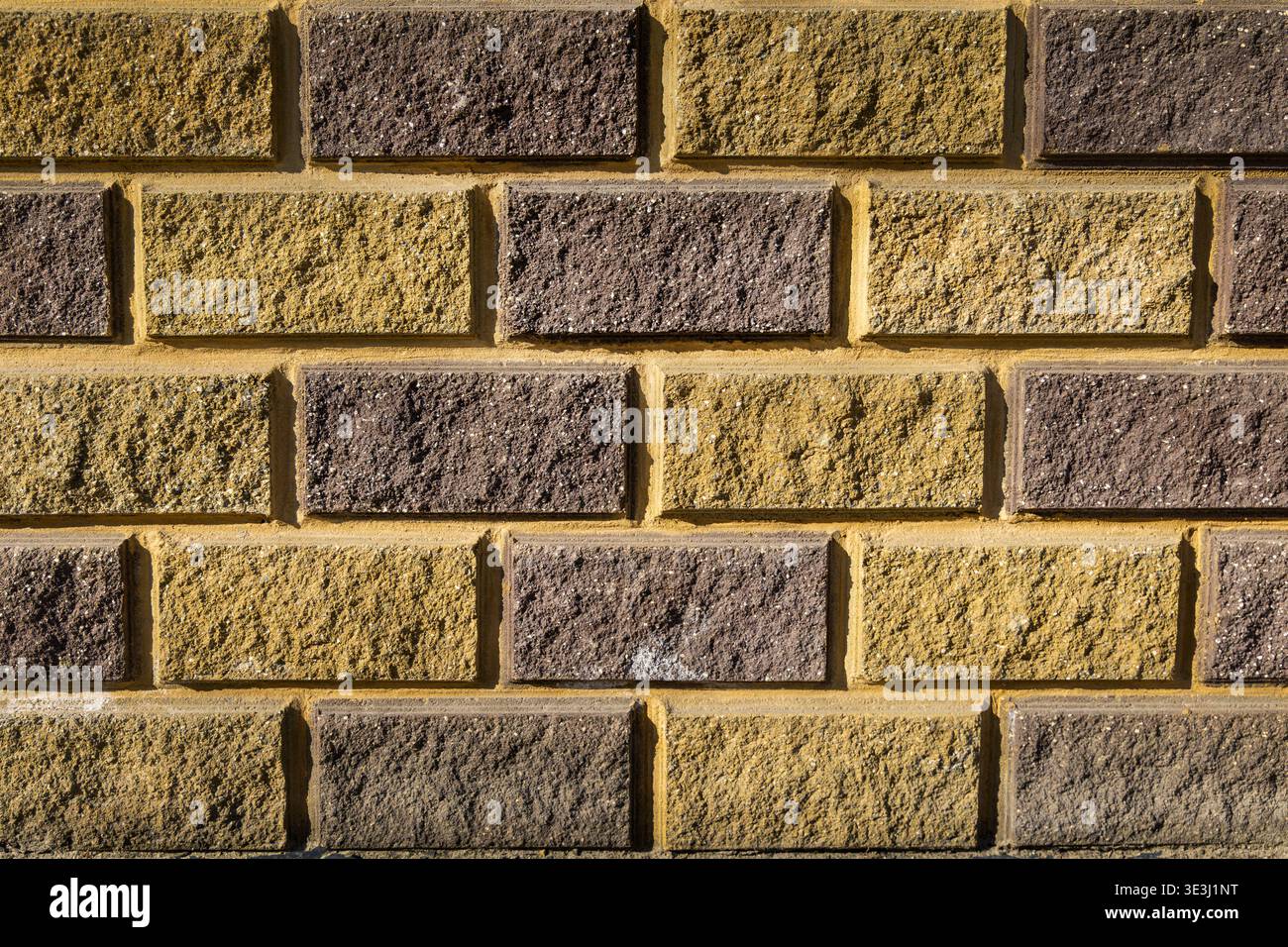 Gelber und brauner Backsteinwand Textur Hintergrund. Vollrahmennaht einer gelben und braunen Ziegelwand mit rauer Oberfläche und Mörtellinien, ideal als Stockfoto