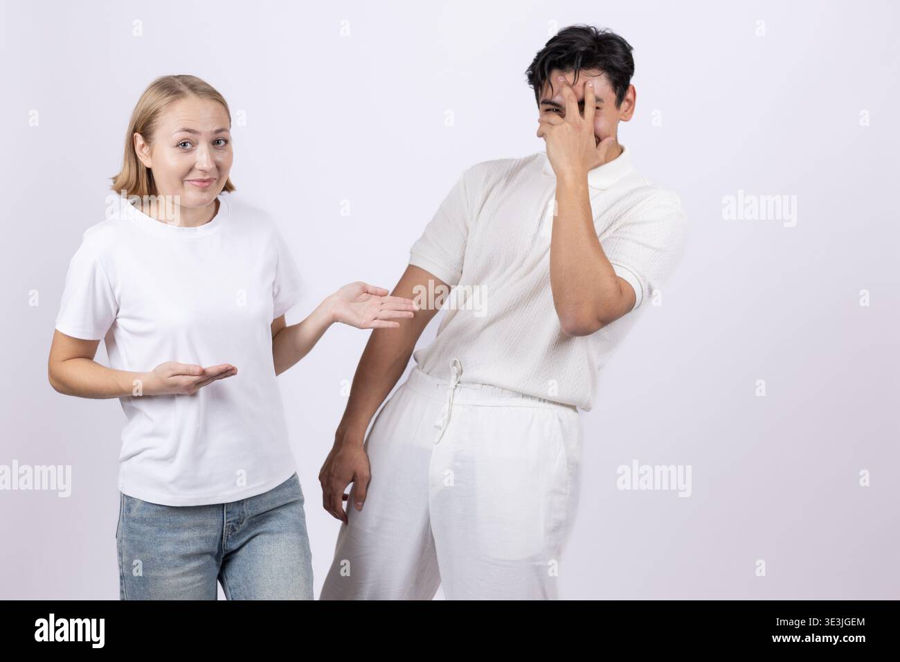 Eine junge Frau, die auf einen Mann zeigt, während sie auf weißem Hintergrund steht Stockfoto