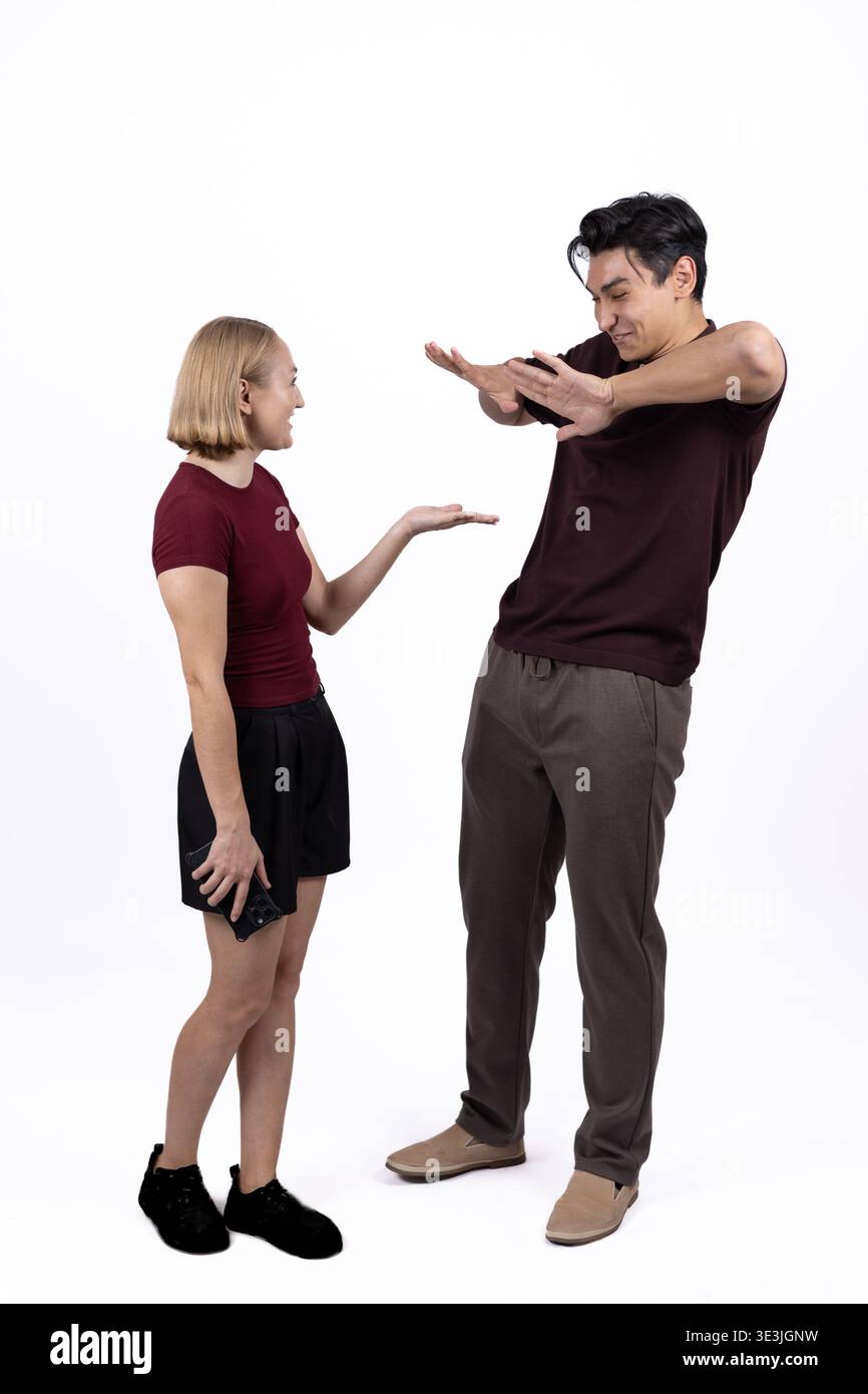 Eine junge Frau, die einen Mann beschuldigt, der in einem Studio verwirrt aussieht Stockfoto