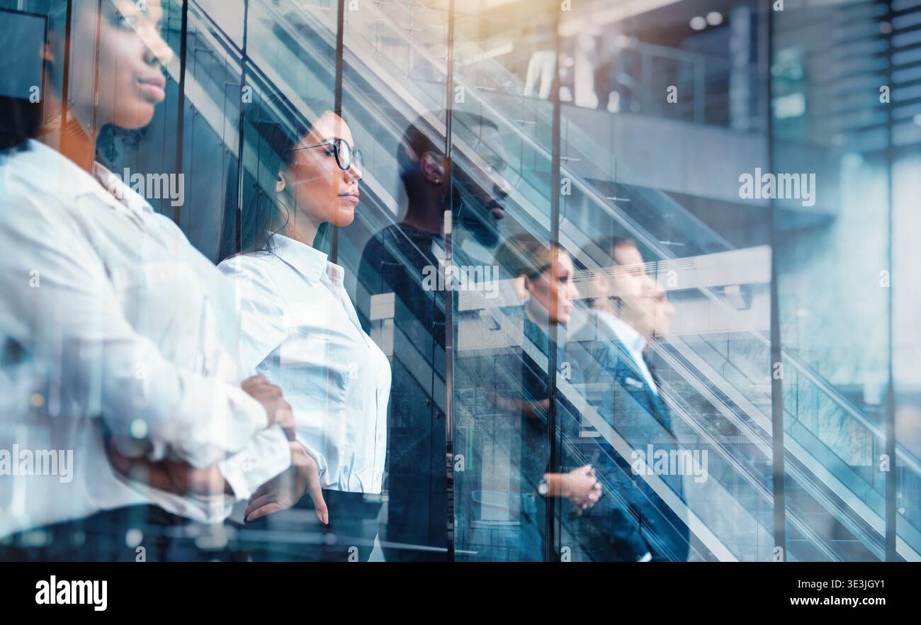 Die Menschen stehen tagsüber in einer Schlange in einem Bürogebäude mit Glasreflexen, die ihren ernsten Ausdruck und ihre Umgebung zeigen Stockfoto
