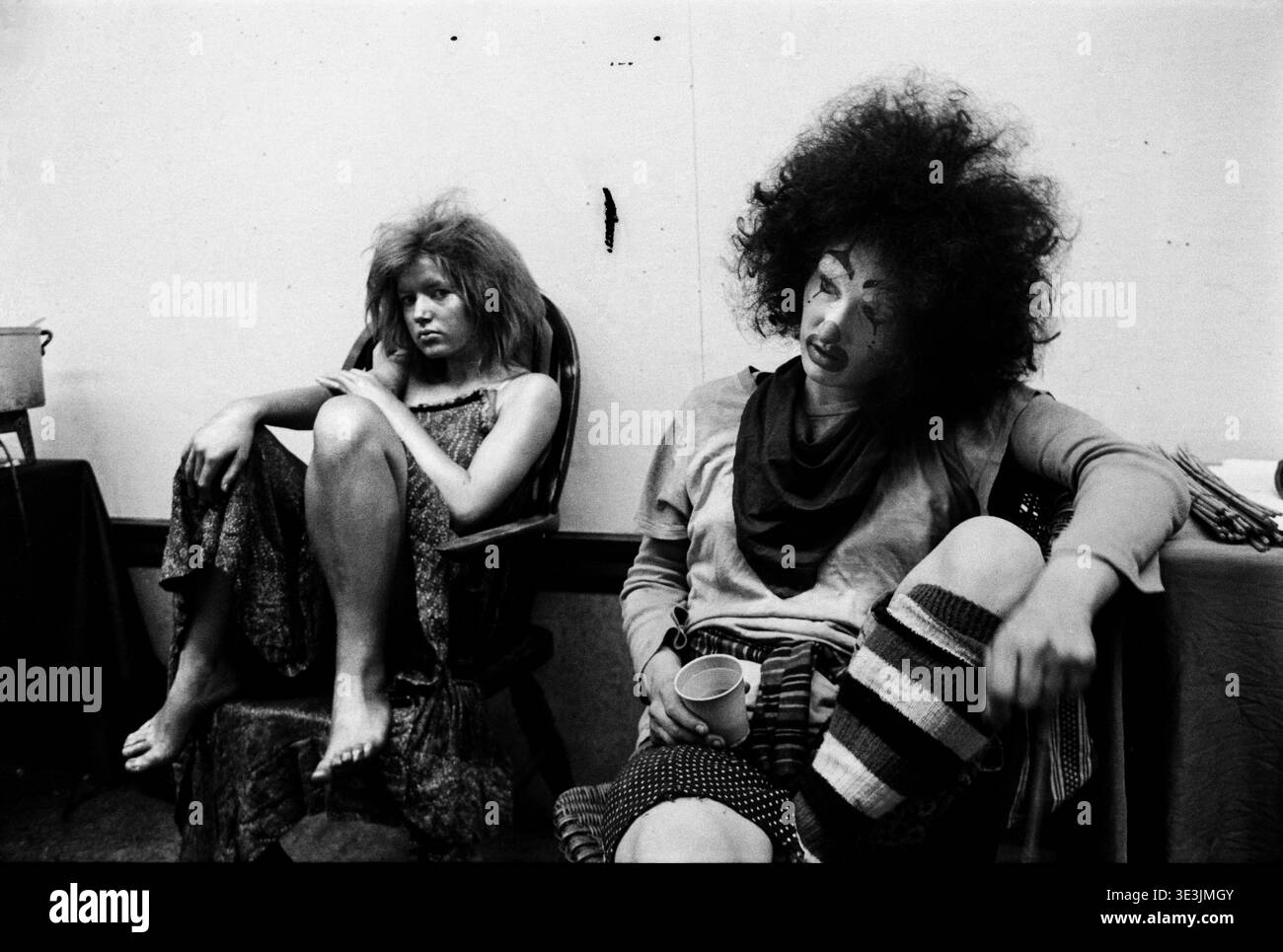 Zwei Clowns entspannen sich nach Performimg mit der Community Art Group Action Space's Play Optional' Event in Coventry, 1973. Der Clown auf der linken Seite ist mit silberner Korpusfarbe bedeckt. Stockfoto
