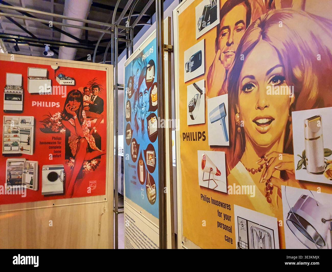Drei klassische Philips Werbetoster aus der Mitte des 20. Jahrhunderts in einer Innenausstellung. Das linke Poster ist rot Stockfoto